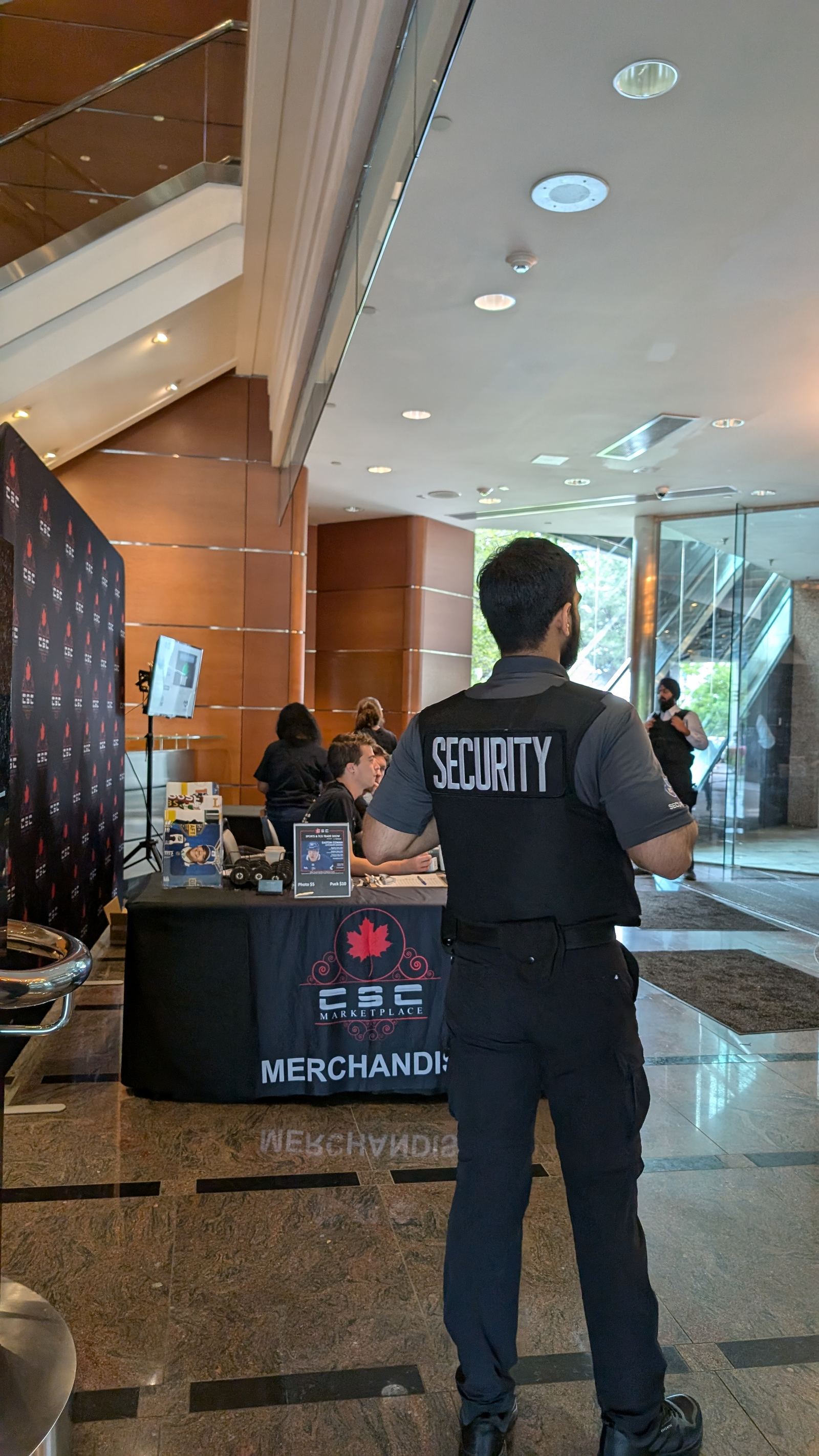 A KingsGuard guard watching a merchandise sales table set up in the lobby of a commercial tower